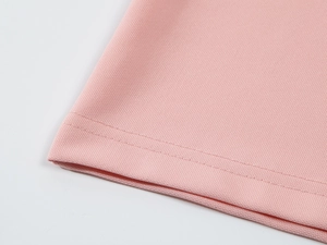 Gros plan du polo rose en soie glacée avec texture alvéolée respirante et coutures de précision