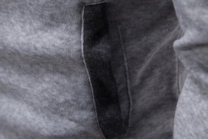 Detailed close-up of side pocket and charcoal grey knit fabric on men's hoodie jacket