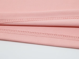 Détail de la couture à double aiguille sur l'ourlet du polo en soie glacée rose