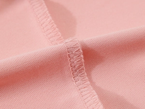 Gros plan du polo en soie glacée rose avec coutures précises et texture de tissu de qualité