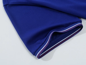 Close-up of polo shirt cuff with red, white, and blue striped ribbing on blue pique fabric