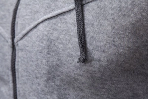 Macro shot of gray heather knit fabric and black braided drawstring on hoodie