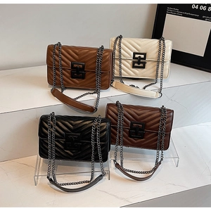Quilted chain shoulder bags in caramel, white, and black on a marble display