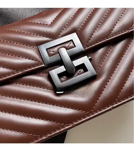 Detail of brown quilted leather texture and dark matte metal buckle on shoulder bag