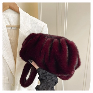 Détail d'un sac seau plissé en fausse fourrure bordeaux avec une texture douce et pelucheuse