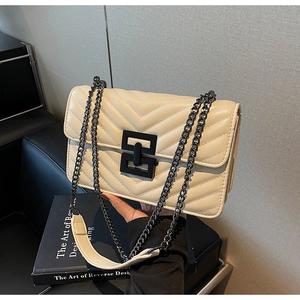 Close-up of quilted cream crossbody bag with V-shaped stitching and matte black chain strap