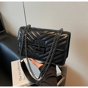 Detail of black quilted leather shoulder bag with sleek metal chain and square lock