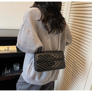 Rear view of a model wearing the black V-quilted chain strap bag with geometric clasp detail