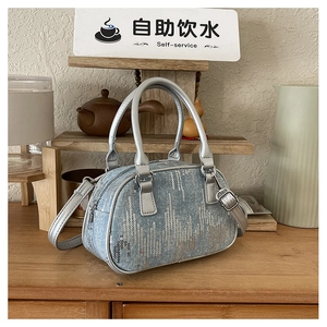 Detail of blue denim crossbody bag with wavy silver sequins and cylindrical handles