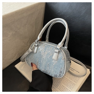 Close-up of a stylish silver sequin crossbody bag placed on an open book for detail