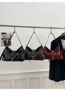 Detailed view of three polished faux leather baguette bags hanging on a metal bar