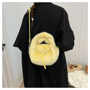 Detail of soft yellow plush handbag on model with contrast black outfit and leather straps