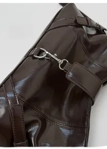 Detailed close-up of glossy dark brown leather stitching and silver metal buckle hardware