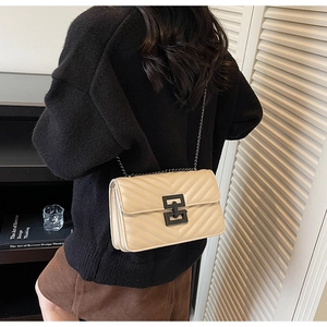 Close-up of beige quilted crossbody bag with V-shaped stitching and black metal lock