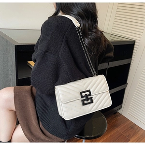 Rear view of a model wearing a white quilted crossbody bag with black metal chain strap