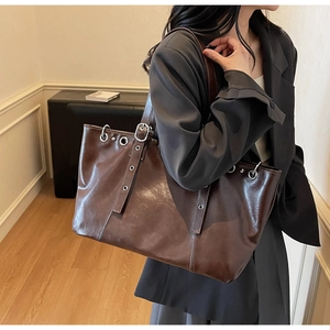Macro shot of dark brown faux leather tote with metallic eyelets and adjustable strap