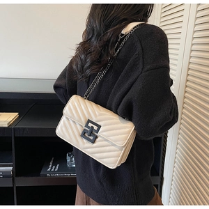 Detail of cream quilted crossbody bag with modern geometric buckle and chain strap