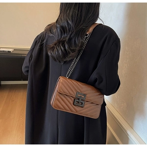 Detail of brown quilted crossbody bag with chevron stitching and black chain strap