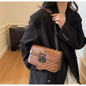 Detail of V-shaped chevron stitching and matte black interlocking metal clasp on bag