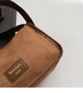Close-up of premium brown suede fabric with brand leather patch and neat stitching