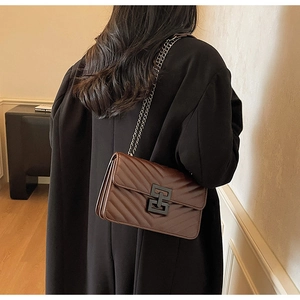 Detail of dark brown crossbody bag with V-quilted texture and metal chain strap