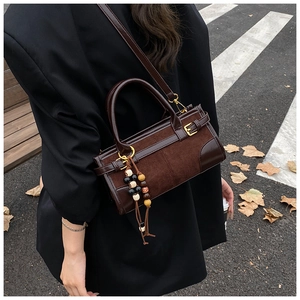 Detail of vintage coffee crossbody bag featuring suede textures and beaded tassel charm