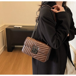 Detail of V-shaped quilted brown leather crossbody bag with black metallic buckle