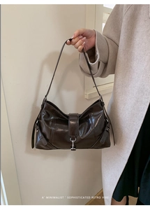 Detail of dark brown glossy leather dumpling bag with silver buckle and retro vibe