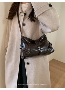 Detail of vintage dark brown oil-wax leather shoulder bag with metal hook closure