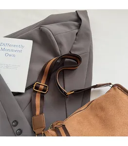 Detail of a brown canvas shoulder bag with a striped wide strap on a grey suit jacket