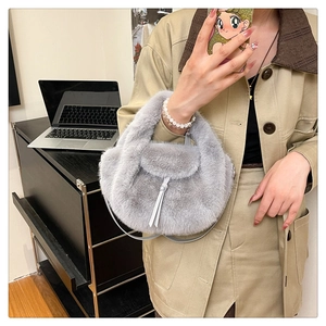 Detailed close-up of a grey plush handbag featuring soft faux fur and elegant tassel trim