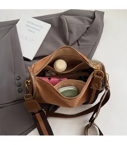Top view of suede cylinder shoulder bag showing organized interior with personal items
