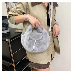Close-up of grey faux fur handbag texture with leather drawstring on a female model