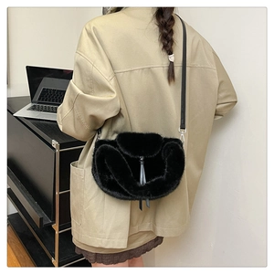 Detail of a fluffy black plush crossbody bag with leather tassels on a stylish model