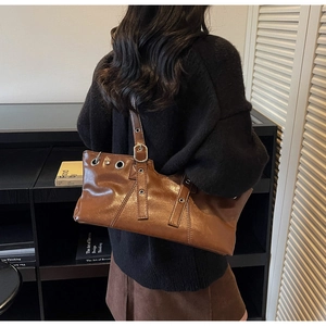 Detail of vintage brown glossy leather shoulder bag with large metal ring buckle