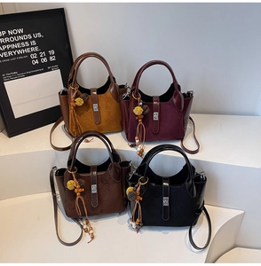 Detail view of stylish patchwork bucket bags in four colors with furry pompom charms