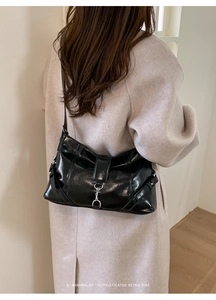 Borsa baguette nera minimalista con fibbia argento indossata da modella in stile retro