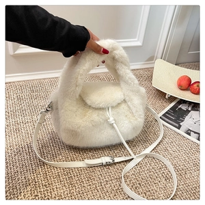 Close-up of white plush crossbody handbag showing soft faux fur texture and leather strap