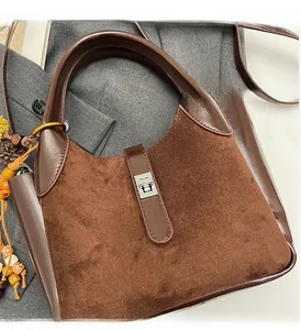 Detail of dark brown suede bucket bag with metallic buckle and elegant pearl accessory