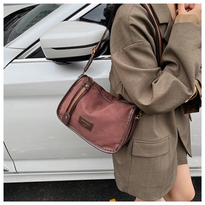 Detail of vintage burgundy canvas crossbody bag with brown leather trim and wide strap