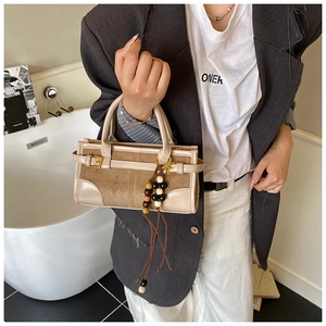 Close-up of retro color-block handbag with wooden bead charm and suede details