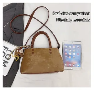 Macro di una borsa a secchiello scamosciata marrone con orsetto e dettagli borchie