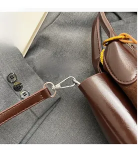 Detail of silver alloy hook and glossy dark brown leather finish on a bucket bag