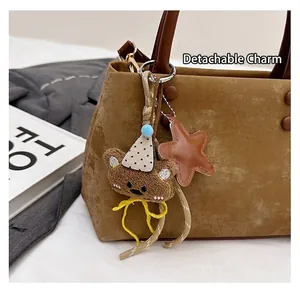 Dettaglio del ciondolo a forma di orsetto e stella in pelle su una borsa a mano