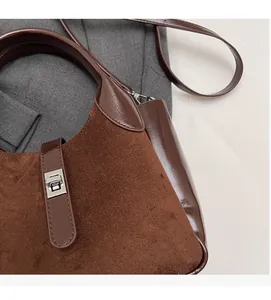 Detail of the brown suede and smooth leather bag featuring a silver metal twist lock