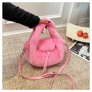 Close-up of pink faux fur handbag featuring leather shoulder strap and drawstring detail