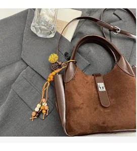 Detailed macro view of the brown bucket bag featuring a silver lock and floral pendant decoration