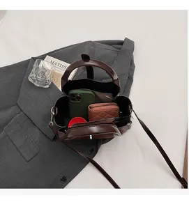 Top-down view of spacious interior of dark brown leather bucket bag with daily items