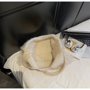Detail of off-white knit beanie with tassel trim and breathable mesh texture