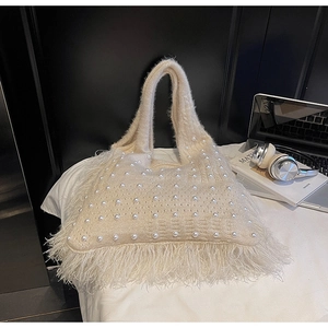 Detail of cream knit tote bag with pearl embellishments and long fringe accents